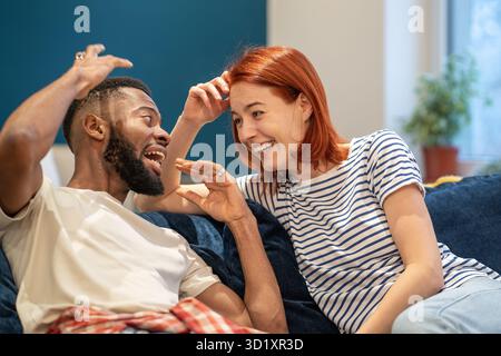 Giovane coppia familiare interrazziale felice marito e moglie che si legano a casa, parlando e ridendo Foto Stock