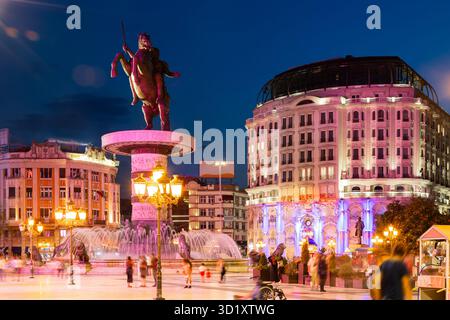 Piazza Macedonia a Skopje al tramonto con fontane illuminate danzanti e statua di Alessandro Magno sullo sfondo Foto Stock