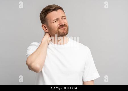 Ritratto di un uomo di mezza età che soffre di osteocondrosi cervicale che tocca il collo sfregato. Foto Stock