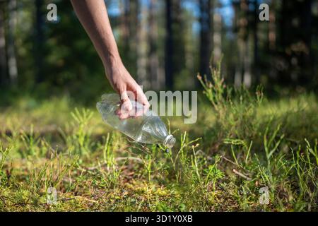 Attivista eco nella foresta trova rifiuti lasciati indietro, raccoglie bottiglie di plastica per preservare l'ambiente pulito Foto Stock
