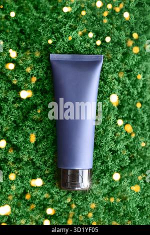 Tubetto di crema blu scuro. Disteso sul muschio verde. Vista dall'alto. Cura quotidiana della casa per la pelle del viso e del corpo. Crema solare. Personale h Foto Stock