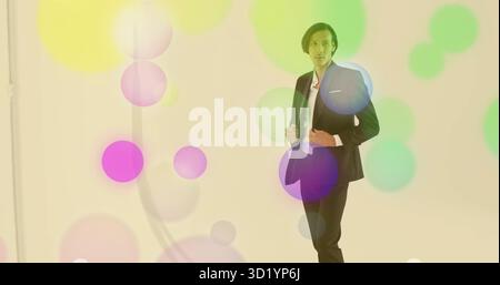 Modello regolabile con giacca nera, pantaloni in studio con cerchi colorati e clip per microfono Foto Stock