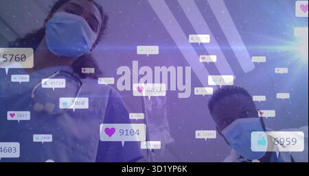 Peering mascherato operatori sanitari in scrub in stanza clinica, con icone fluttuanti di social media Foto Stock