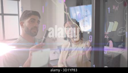 Coppia in collaborazione che indossa abiti formali analizzando i dati nella sala riunioni, con lavagna di vetro Foto Stock