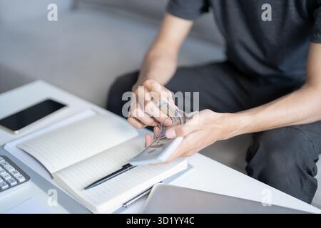 L’uomo calcola banconote monetarie finanzia economia di risparmio casa paga bollette tasse finanziarie a casa Foto Stock