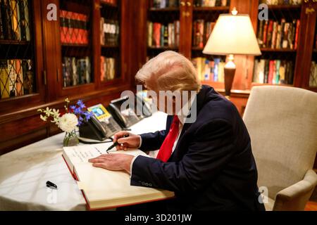 Il presidente Donald Trump firma il libro degli ospiti presso la residenza dell'ambasciatore a Tokyo, in Giappone martedì 28 ottobre 2025, come segretario del commercio Howard Lutnick, ambasciatore George Glass, e sua moglie Mary Glass, guardano su. (Foto ufficiale della Casa Bianca di Molly Riley) Foto Stock