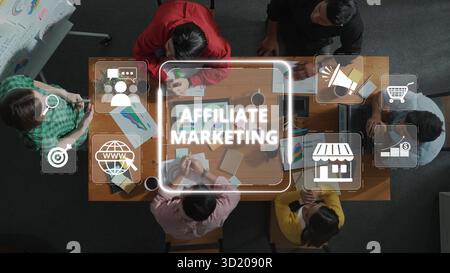 Una vista dall'alto verso il basso cattura un gruppo eterogeneo di professionisti impegnati in un incontro collaborativo che discute le strategie di marketing di affiliazione con ic digitale Foto Stock