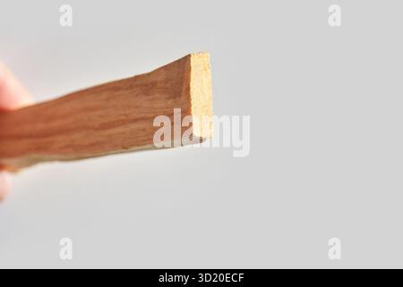 Vista ravvicinata di un bastoncino di legno tenuto con uno sfondo chiaro focalizzato sulla consistenza Foto Stock