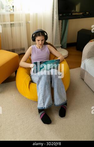 I giovani amano trascorrere il proprio tempo libero in un accogliente salotto mentre utilizzano un computer portatile e indossano le cuffie Foto Stock