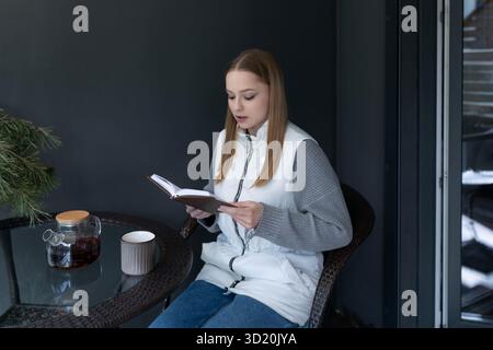 Leggere un libro mentre si gusta un caffè in un'accogliente mattinata d'inverno in un moderno spazio interno Foto Stock