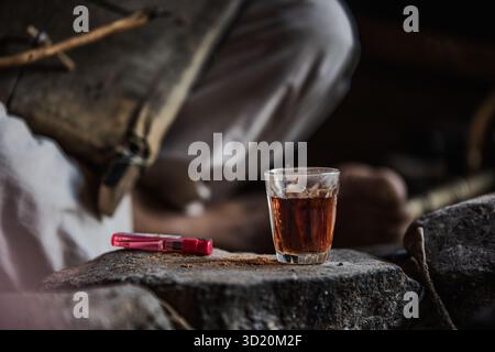 Un bicchiere di tè beduino e un leggero riposo accanto a uno strumento di rababa fatto a mano all'interno di una tenda del deserto, Wadi Rum, Giordania. Foto Stock