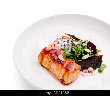 Salmone deliziosamente placcato con verdure e barbabietole presentate elegantemente su un piatto bianco Foto Stock