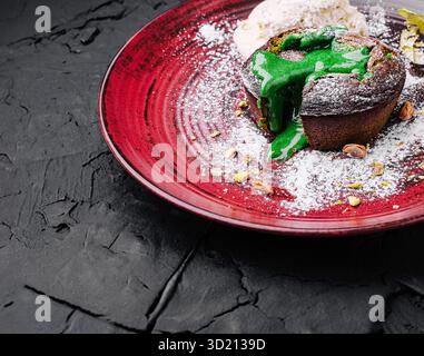 Dessert con vivace ripieno verde servito con gelato su sfondo nero testurizzato in un ristorante moderno Foto Stock