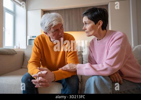 Moglie amorevole che si tiene per mano con un marito serio e in angoscia sul divano che offre un supporto emotivo Foto Stock