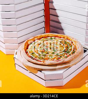 Deliziosa pizza servita su una tavola di legno con pile di scatole vuote in un ambiente vivace Foto Stock