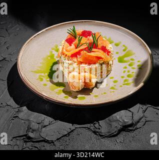 Piatto gourmet a base di pesce con salmone e gamberi su un piatto testurizzato guarnito con erbe e salsa in un ambiente buio Foto Stock