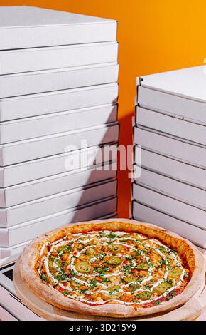 Deliziosa pizza servita su una tavola di legno con pile di scatole vuote in un ambiente vivace Foto Stock