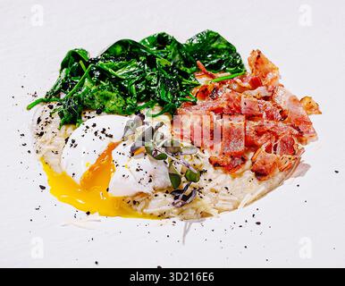 Delizioso piatto da colazione con uova in camicia, verdure e pancetta croccante su un vivace sfondo blu Foto Stock