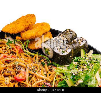 Delizioso piatto di ispirazione asiatica con spaghetti, sushi roll, pollo croccante e insalata fresca Foto Stock