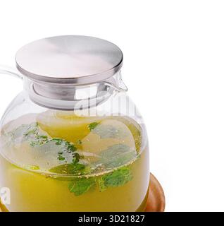 Tè alle erbe fresco in una caraffa di vetro con foglie di menta su un vassoio di legno Foto Stock