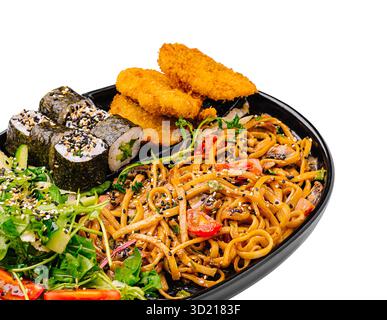 Delizioso piatto di ispirazione asiatica con spaghetti, sushi roll, pollo croccante e insalata fresca Foto Stock
