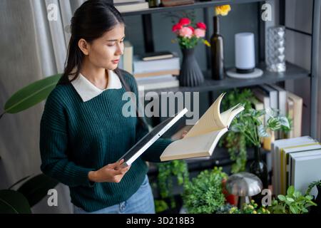 Donna asiatica che impara a conoscere le energie rinnovabili il controllo remoto dell'energia solare nella sua casa e l'installazione di pannelli solari sostenibili technolo Foto Stock