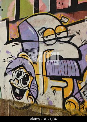 Due simpatici personaggi dei cartoni animati dipinti con vernice spray su una parete di cemento come graffiti Foto Stock