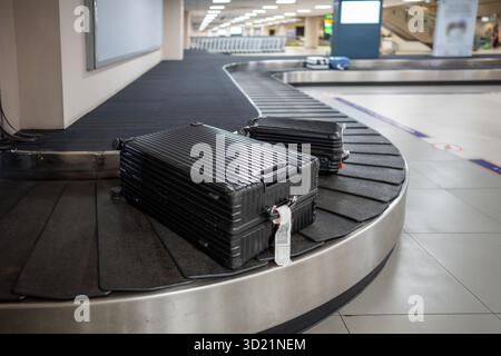 Caricamento dei bagagli spostamento sul nastro trasportatore durante lo scarico post-volo. I bagagli viaggiano in anticipo verso l'area di ritiro, i passeggeri aspettano il ritorno Foto Stock