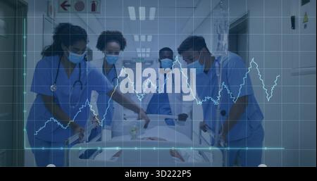 Squadra medica che indossa maschere e stetoscopi che spingono il paziente sulla barella in basso corridoio con ECG Foto Stock