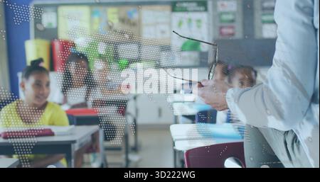 Insegnante che tiene gli occhiali e parla con gli studenti in classe, con scrivanie, poster, spazio per le copie Foto Stock