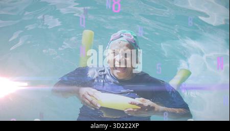 Nuotatore senior galleggiante che tiene spaghetti gialli nella piscina all'aperto, indossa un berretto e occhiali di protezione rosa Foto Stock