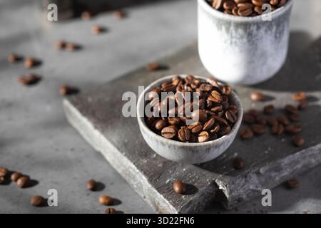 Chicchi di caffè arrosto in una ciotola su una tavola grigia. Foto Stock