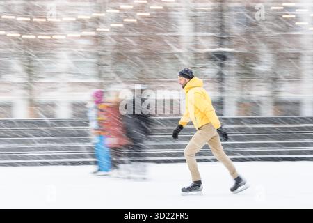 Uomo barbuto di mezza età sulla pista di pattinaggio su ghiaccio, all'aperto nelle giornate invernali innevate Foto Stock