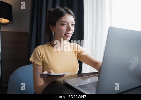 Giovane donna ispanica Gen Z che prenota i biglietti del volo online sul laptop in stile di vita moderno. Foto Stock