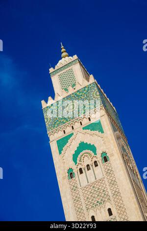 Torre di una moschea decorata in modo intricato con motivi geometrici contro un cielo azzurro. Casablanca, Marocco Foto Stock