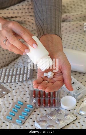 Mani femminili che versano pillole dal flacone al palmo in blister Foto Stock