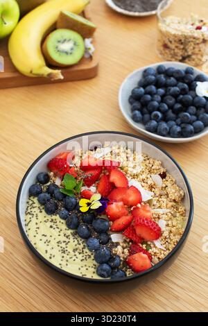 Sana prima colazione con frullato di avocado con frutta fresca e semi di chia su un tavolo di legno. Cibo vegano Foto Stock