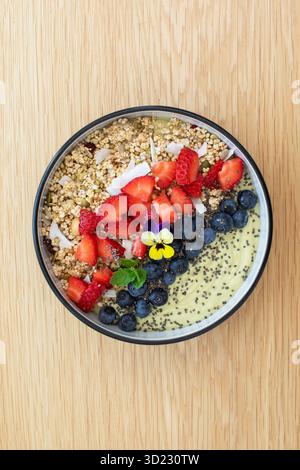 Sana prima colazione con frullato di avocado con frutta fresca e semi di chia su un tavolo di legno. Cibo vegano Foto Stock
