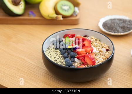 Sana prima colazione con frullato di avocado con frutta fresca e semi di chia su un tavolo di legno. Cibo vegano Foto Stock