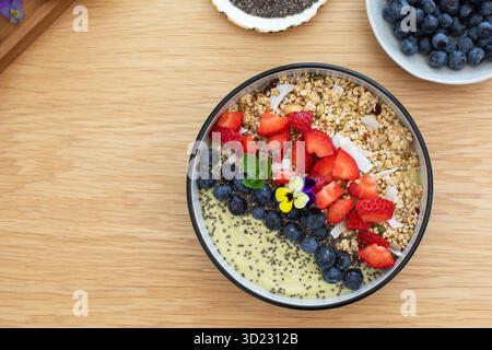 Sana prima colazione con frullato di avocado con frutta fresca e semi di chia su un tavolo di legno. Cibo vegano Foto Stock