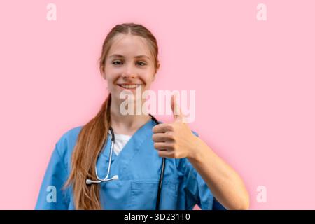 Giovane donna caucasica dottore in uniforme blu su sfondo rosa isolato regala un pollice in alto Foto Stock