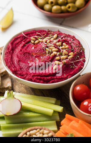 Hummus di barbabietola in una ciotola con verdure fresche, sedano, carote, pita. Cibo sano Foto Stock