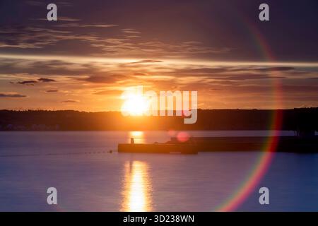 Uno splendido tramonto proietta colori vivaci su un calmo corpo d'acqua con un molo sagomato, Zara, Croazia. Foto Stock