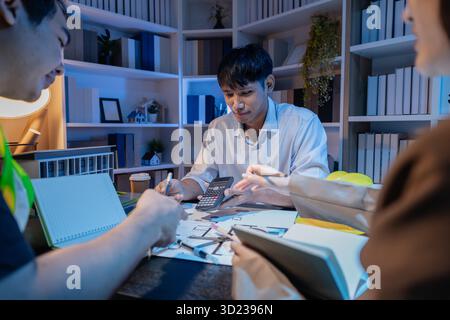 Un team diversificato di professionisti condivide idee su layout architettonici e concetti strutturali, concentrandosi sul lavoro di squadra, la creatività e la precisione in m Foto Stock