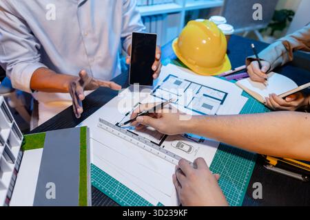 Ingegneri e architetti analizzano i modelli di costruzione e discutono le strategie di progetto, combinando conoscenze tecniche e idee creative per ottenere successo Foto Stock