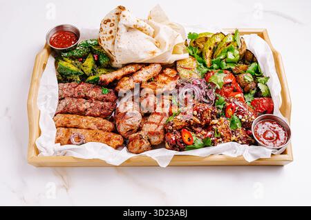 Delizioso piatto di carne con vari piatti alla griglia serviti con salse Foto Stock