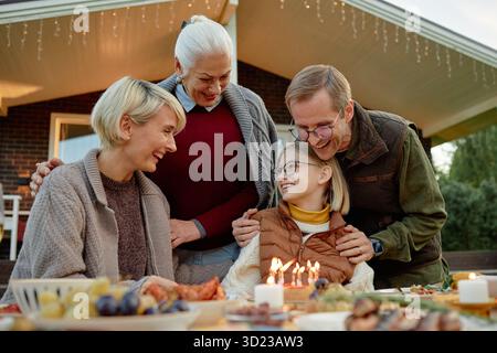Famiglia caucasica che celebra il compleanno all'aperto sorridendo e interagendo insieme Foto Stock