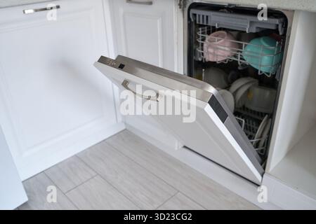 Lavastoviglie a vista con piatti puliti nella moderna cucina con pavimento in legno Foto Stock