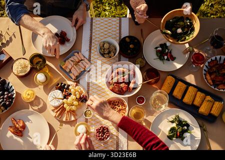 Gruppo di persone che condividono un pasto all'aperto e si godono il cibo insieme Foto Stock