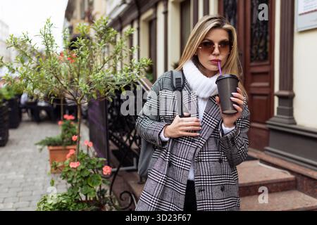 Donna turistica con una tazza di caffè sullo sfondo di una bella strada Foto Stock